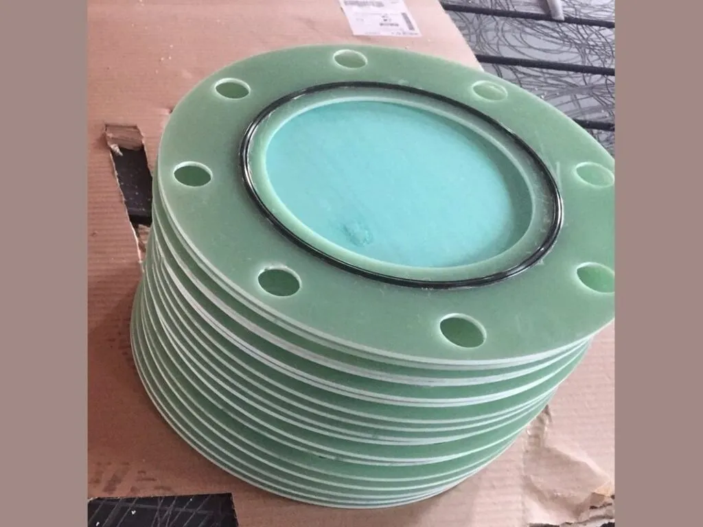 Bộ gioăng cách điện mặt bích: Chồng gioăng cách điện sợi thủy tinh xanh lục có lỗ bu lông xếp trên thùng giấy