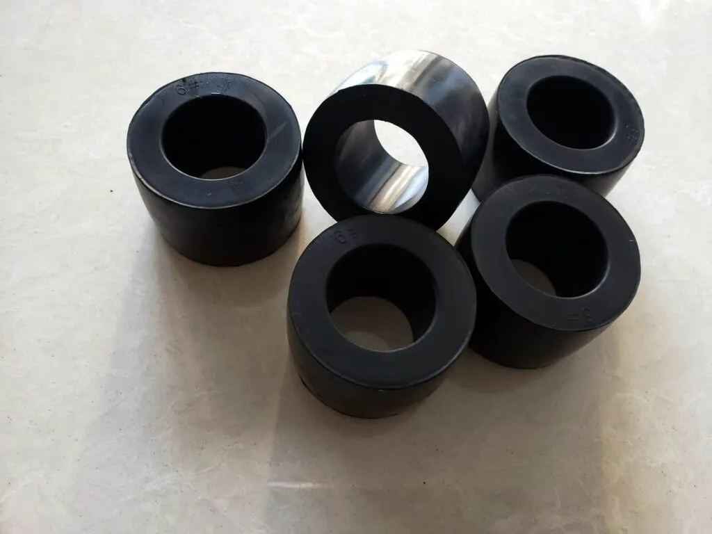 Cao su khớp nối chốt: Bốn bạc cao su đen hình trụ rỗng đặt cạnh nhau trên nền sáng