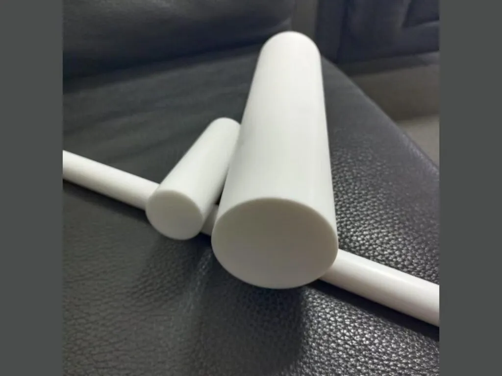 Cây nhựa teflon PTFE: Cây teflon phi lớn và phi nhỏ đặt chéo trên một cây PTFE dài mảnh