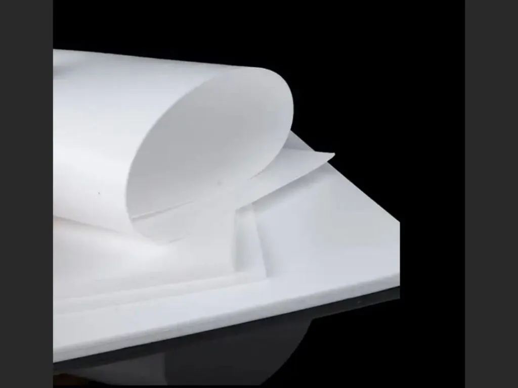 Gioăng PTFE biến tính: Tấm PTFE trắng cuộn nhẹ phía trên chồng tấm phẳng dày