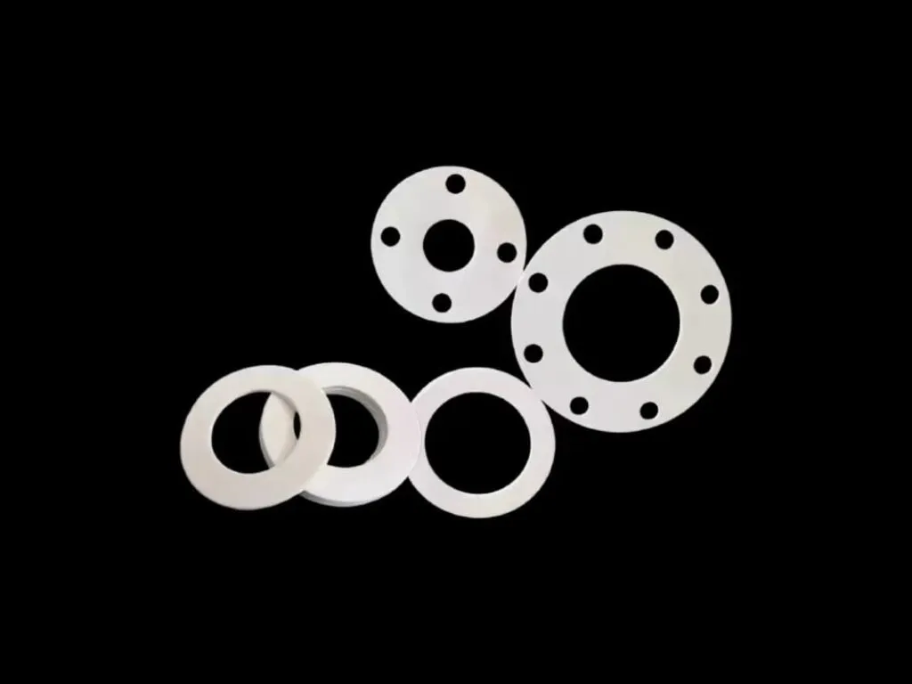 Gioăng PTFE mặt bích: Bốn gioăng PTFE trắng có lỗ bắt bu lông xếp trên nền đen