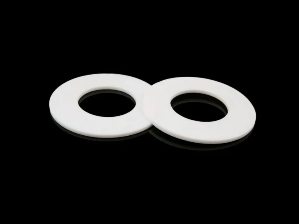 Gioăng PTFE mặt bích: Hai gioăng PTFE trắng phẳng nhìn nghiêng, lỗ giữa tròn
