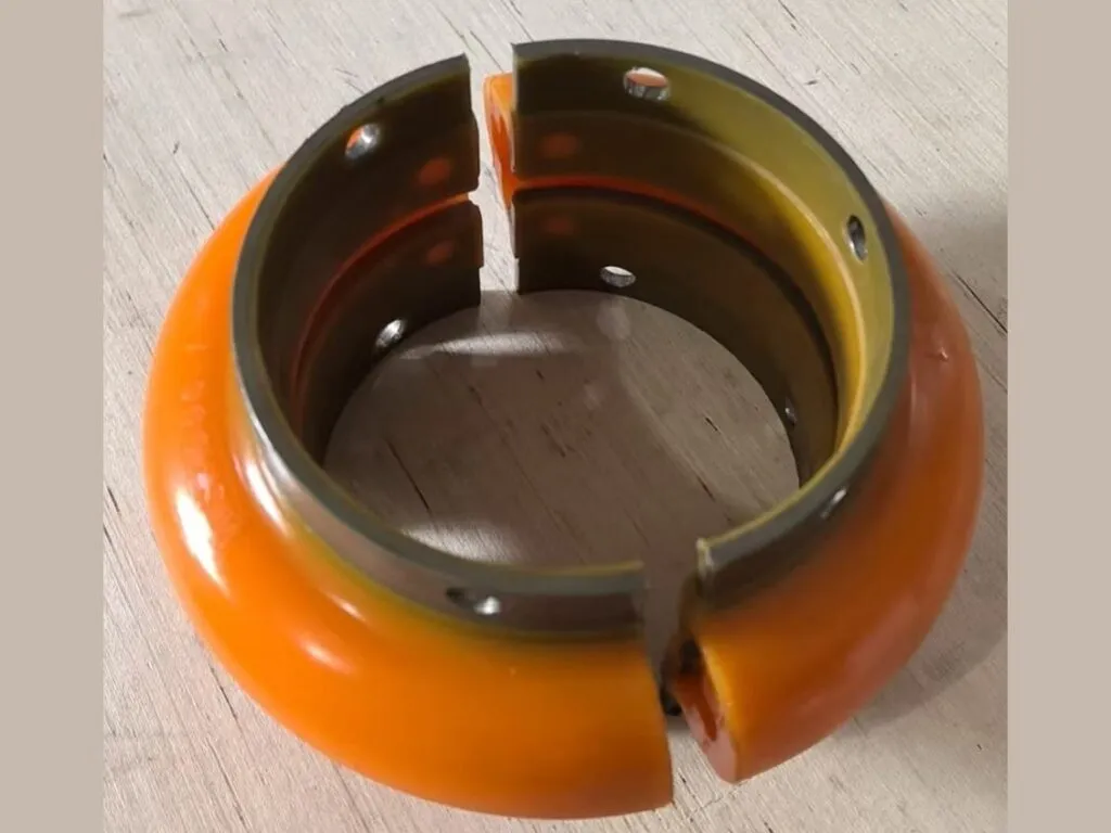 Khớp nối omega: Nửa khớp nối omega cam có khe cắt và vành kim loại đặt trên nền gỗ
