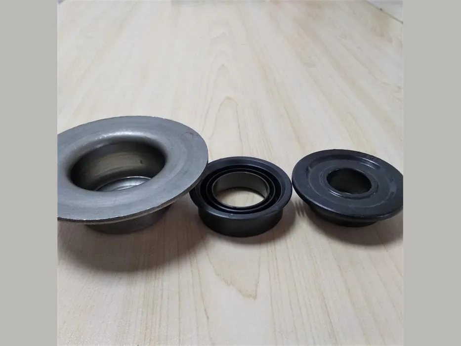 Phớt chắn bụi ổ trục: Chén thép và hai vòng cao su đen đặt trên mặt gỗ sáng
